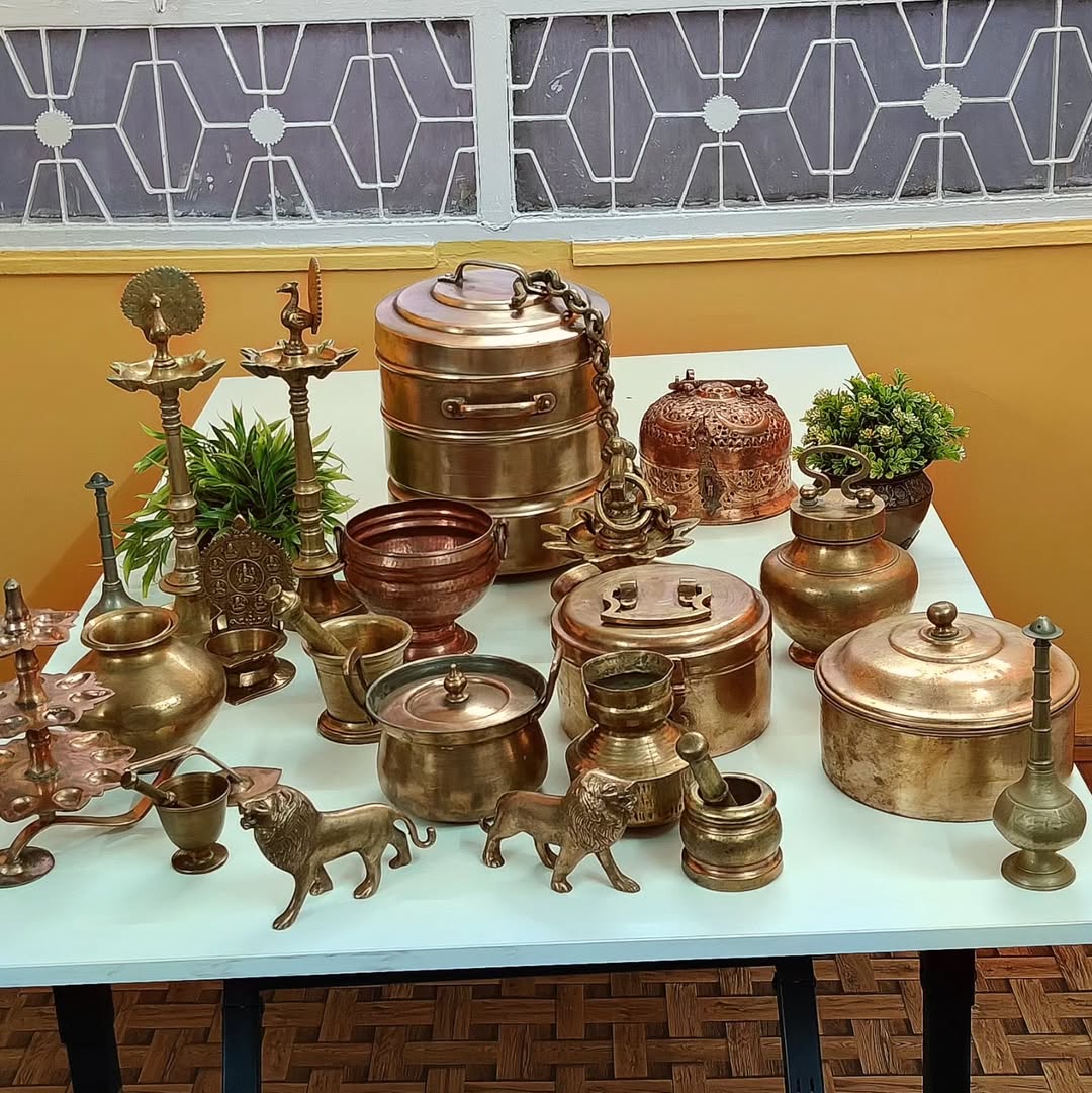 Elegant antique brass and copper utensils displayed on a table, highlighting their traditional craftsmanship and aesthetic appeal in Indian kitchens.